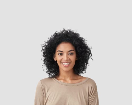 Smiling delighted young African American female has gentle smile, has white teeth, rejoices meeting with colleagues, dressed in casual clothes, isolated over white background with blank space