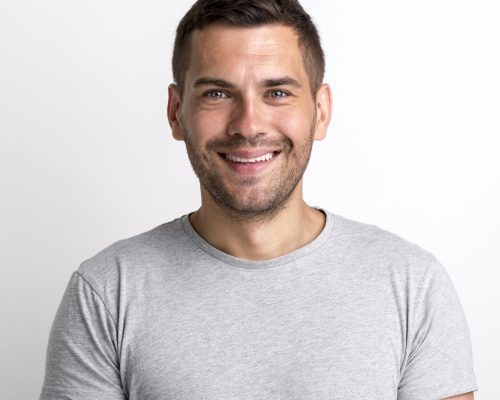 portrait-smiling-charming-young-man-grey-t-shirt-standing-against-plain-background